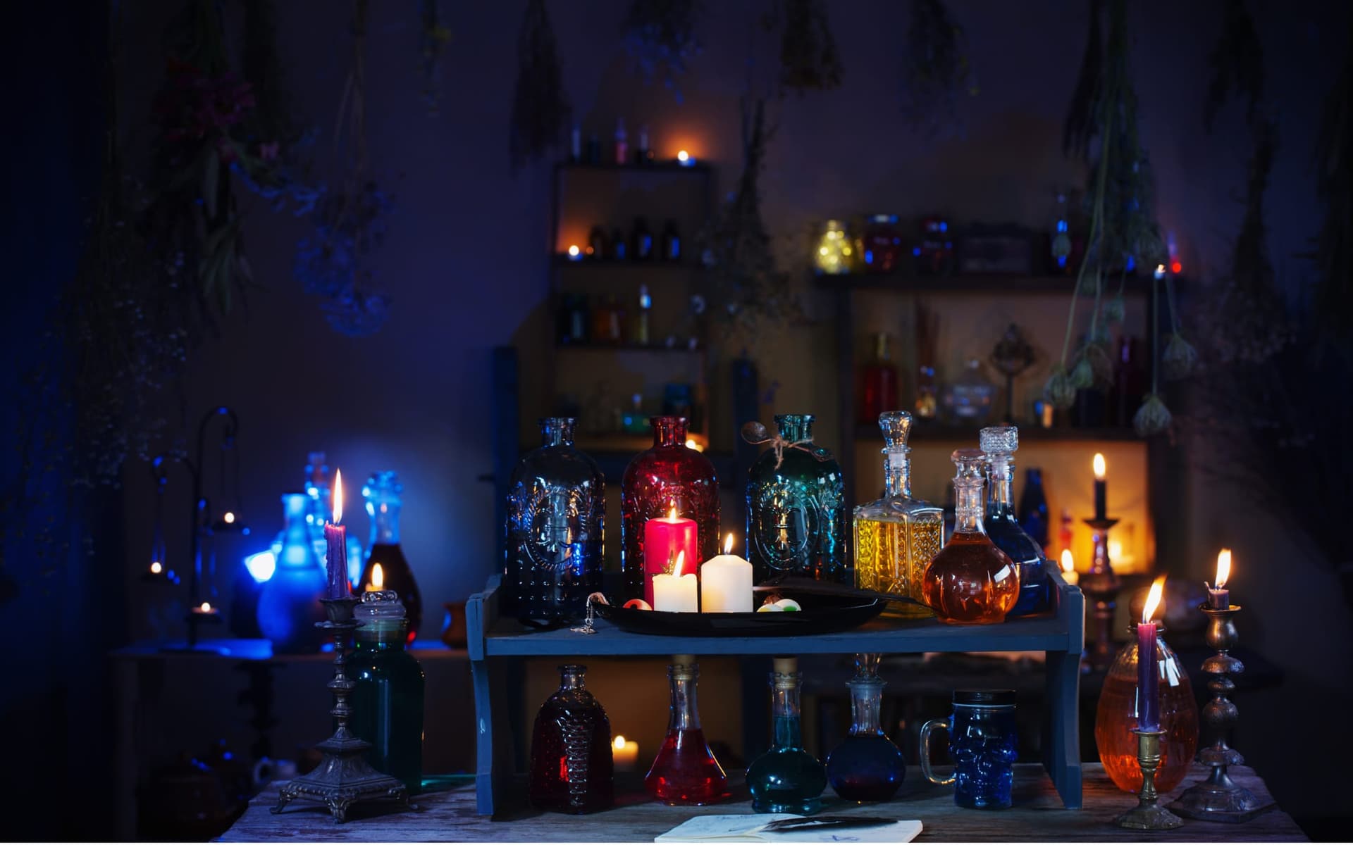 Laboratorio de pociones con frascos de colores, velas encendidas y hierbas secas.